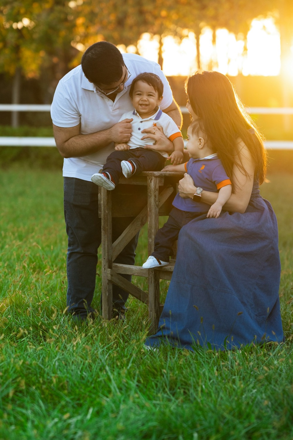 Papás jóvenes jugando con sus gemelos al atardecer